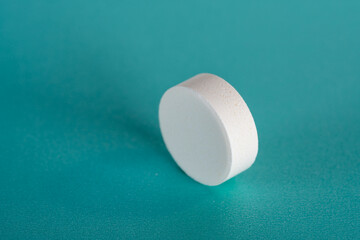 White medicine tablet standing on side on blue pastel background as macro 2