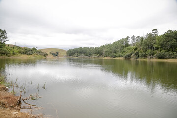 Foto de uma ponte cruzando uma represa em meio à natureza. As águas calmas refletem a estrutura e a vegetação ao redor, compondo uma cena tranquila e harmônica. Ideal para temas de infraestrutura, mei