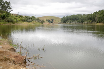 Foto de uma ponte cruzando uma represa em meio à natureza. As águas calmas refletem a estrutura e a vegetação ao redor, compondo uma cena tranquila e harmônica. Ideal para temas de infraestrutura, mei