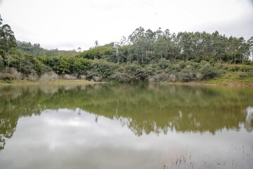 Foto de uma ponte cruzando uma represa em meio à natureza. As águas calmas refletem a estrutura e a vegetação ao redor, compondo uma cena tranquila e harmônica. Ideal para temas de infraestrutura, mei