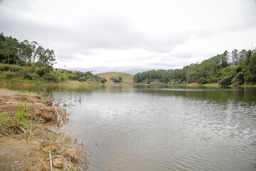 Foto de uma ponte cruzando uma represa em meio à natureza. As águas calmas refletem a estrutura e a vegetação ao redor, compondo uma cena tranquila e harmônica. Ideal para temas de infraestrutura, mei