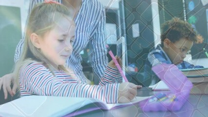 Teacher leaning over girl writing workbook in classroom and showing tablet content in education