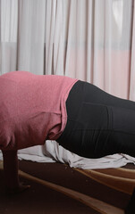 Plussize woman doing yoga stretches in her home, brown skin woman stretching to keep fit