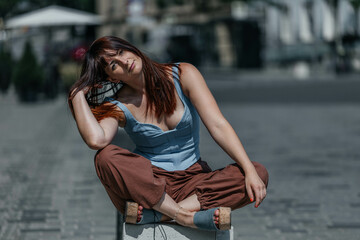 Young caucasian female with red hair sitting cross-legged outdoors on city street