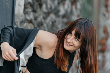 Smiling young caucasian female with long hair in black outfit outdoors