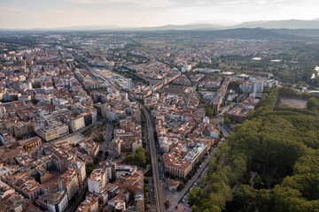 An aerial view of Girona's historic city center, featuring the cathedral, the Onyar River winding...