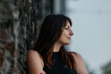 Young caucasian female leaning against brick wall outdoors
