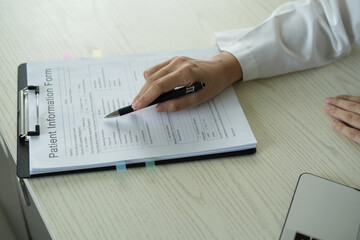 Young asian woman doctor in white uniform with stethoscope taking notes, using laptop, mobile phone, writing in medical journal, professional therapist practitioner filling documents or patient card.
