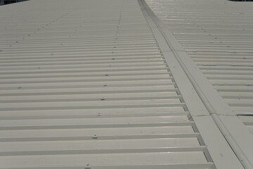 Installation of a specialized ridge cap designed specifically for industrial white sandwich panels. The ridge cap is attached with rivets and sealant to ensure strength and water resistance.