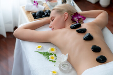 Hot stone massage at spa salon in luxury resort with day light serenity ambient, blissful woman...