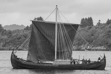 Norwegian Viking merchant ship under full sail in black and white.
