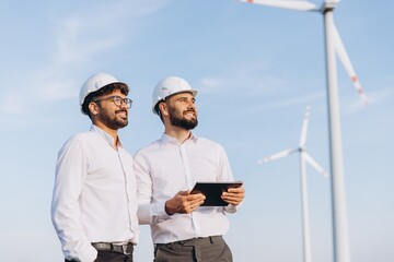 Engineers using tablet working in wind turbine power plant
