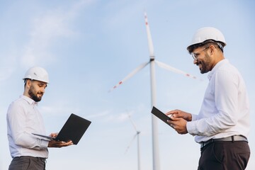 Engineers working with digital devices in a wind turbine power plant