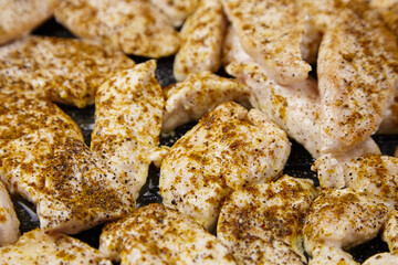 Seasoned chicken fillets are arranged on a grill, showcasing a variety of spices and textures, highlighting the preparation of a delicious meal for culinary enthusiasts