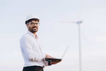 Arabian engineer working with laptop near wind turbine for sustainable energy