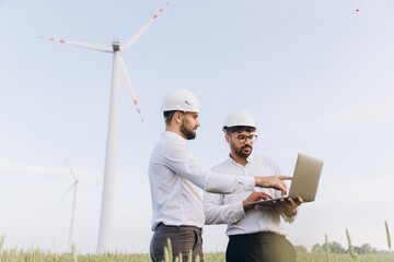 Engineers working on a laptop in a wind turbine field