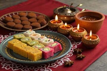 Celebrate diwali with a stunning food arrangement featuring mithai sweets and clay decorations in a festive atmosphere for an unforgettable experience
