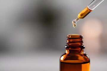 Dropper dripping rose essential oil into small amber glass bottle, close-up with soft natural lighting, layout with copy space