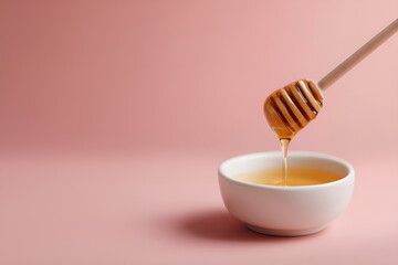 Close-up of dipper dripping golden rose honey into a small bowl, soft pink background, layout with copy space