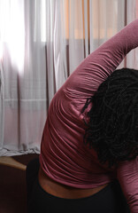 Plussize woman doing yoga stretches in her home, brown skin woman stretching to keep fit