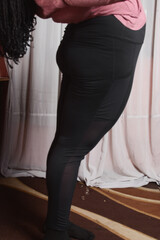 Plussize woman doing yoga stretches in her home, brown skin woman stretching to keep fit