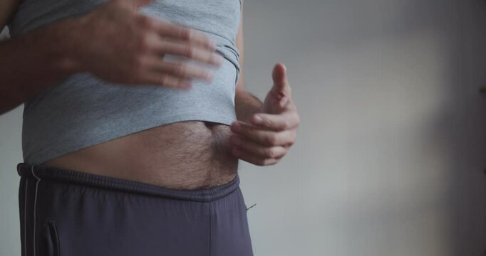 An adult man with a bare hairy beer belly actively gesticulates. Close-up on the stomach and arms