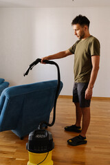 Side view of handsome bearded young man in casual clothes removing dirt and stains using washing...