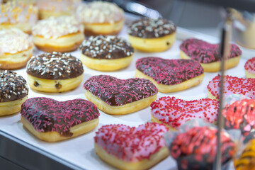 Colorful display of heart-shaped and round donuts in a bakery