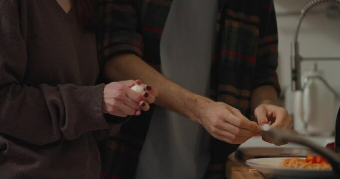 Close up of guy and girl peeling garlic while preparing romantic dinner in cozy kitchen at home in evening. Cooking dinner at home in the evening