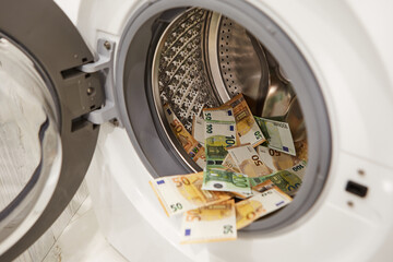 Money, euro laundering in washing machine, closeup view.