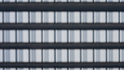 Close-up of a metal facade with repeating vertical stripes and horizontal black bars. Abstract...