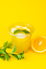 Refreshing Cold Summer Orange Mint Lemonade on Bright Yellow Background