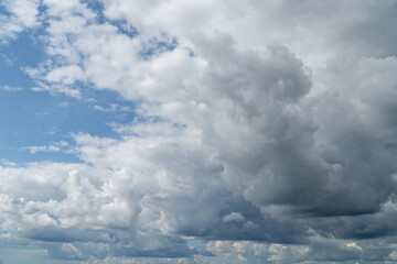 Stormy sky with dark, snowy clouds on a spring day. Clouds are floating across the sky. Dark blue clouds swiftly floating across blue sky. Storm dramatic clouds are floating across the sky. Hurricane.