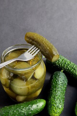 On a gray background there is a glass jar with pickles.