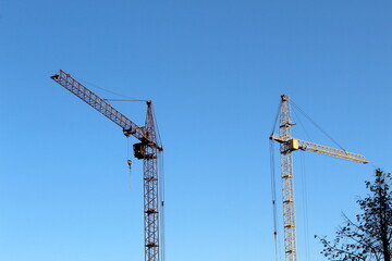 Two high-rise construction cranes stand against the sky.