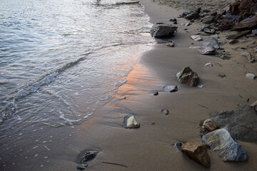 Gentle waves crashing against a sandy beach reflecting a gorgeous, soft pastel sunset