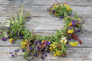 Traditional summer solstice flower crown made from colorful wildflowers and grasses, placed on a...
