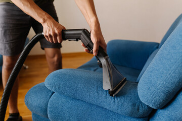 Close-up cropped shot of unrecognizable cleaning service worker using washing vacuum cleaner to...
