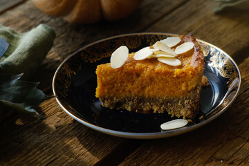 Slice of pumpkin pie sprinkled with sliced almonds. Homemade traditional American thanksgiving pie
