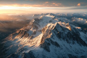 Aerial view of snow-capped mountain ranges at sunrise.  Golden light bathes the peaks, showcasing rugged, icy landscapes.  Vast, dramatic scenery