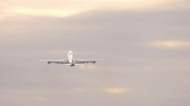 Footage of a four-engine widebody gaining altitude in a beautiful sunset or sunrise sky