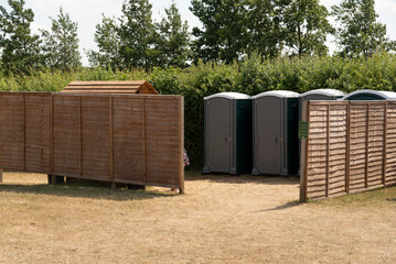 Gloucestershire England UK. 30.06.2025. Toilet block shared by. men and women having the privacy of a fenced screen in the English countryside.