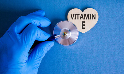 Vitamin E tocopherols symbol. Concept words Vitamin E on beautiful wooden heart. Doctor's hand in...