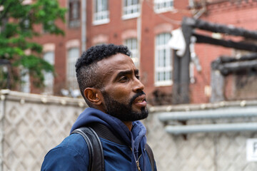 Portrait of a serious adult African American ethnicity man with a beard and glasses. A serious confident black guy a blue jacket posing. Portrait of a black man from Sudan on the blurred background. 