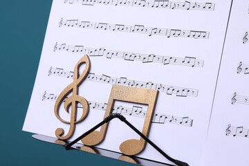 Stand with music sheets and wooden notes on light blue background, closeup