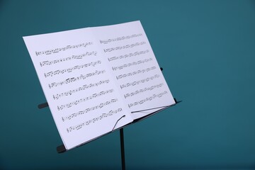 Note stand with music sheets on light blue background, closeup. Space for text