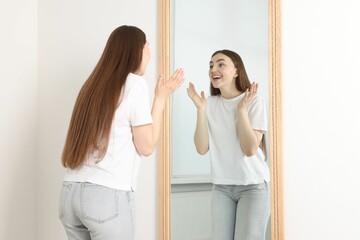 Beautiful woman looking at herself in mirror indoors