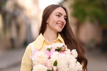 Woman with bouquet of beautiful peonies on city street
