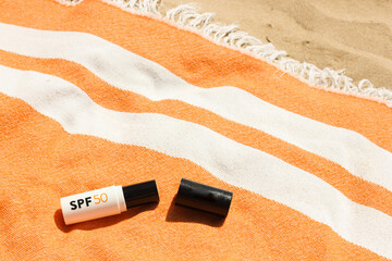 Mineral SPF50 sunscreen stick with UVA + UVB protection on the orange beach towel on the sand near the sea, Beaty routine for healthy skin against sun damage