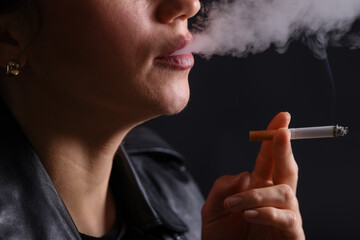 Obraz premium Woman smoking cigarette on black background, closeup